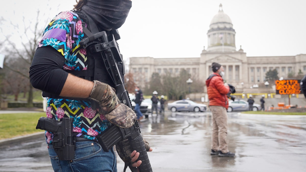 A Black Lives Matter activist carrying a semi-automatic rifle walks outside at the Capitol building in Frankfort, Ky., Wednesday, Jan 17, 2021. The Capitol, the Capitol complex and surrounding grounds have been closed. (AP Photo/Bryan Woolston)