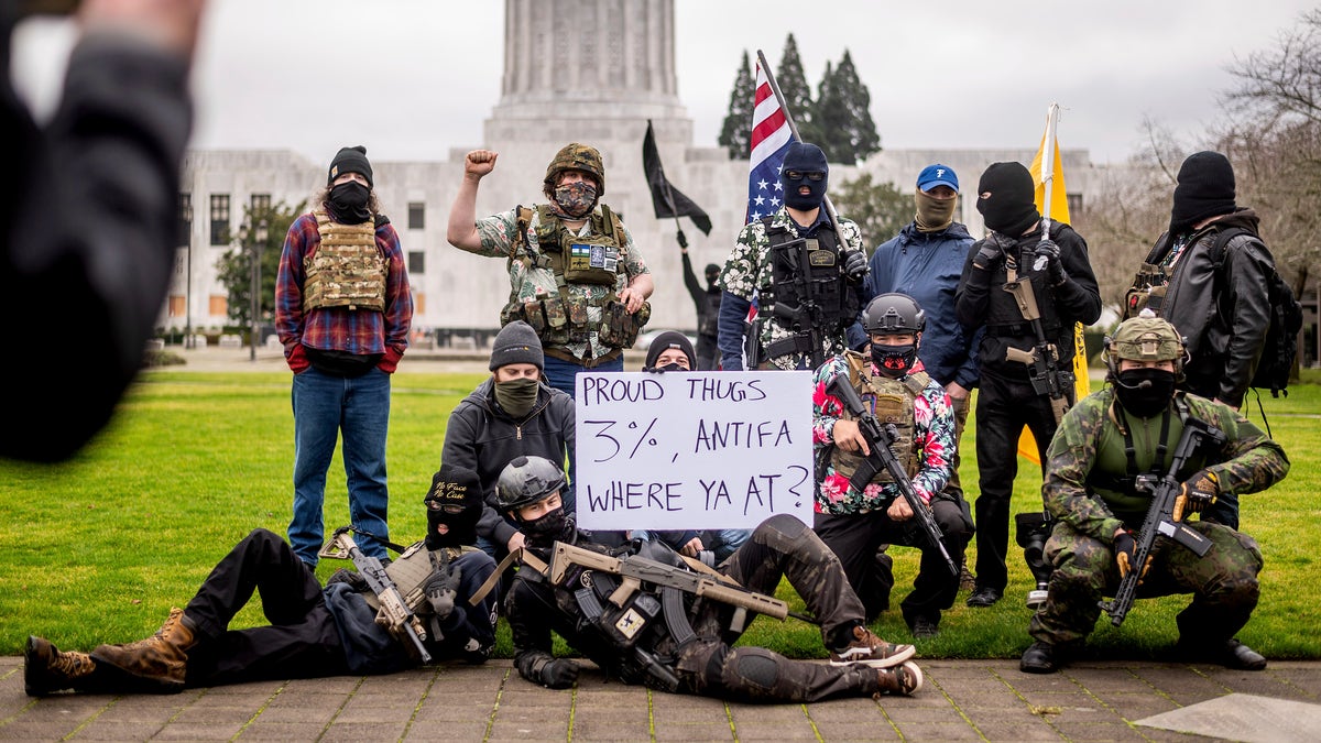 Armed protesters, who identified themselves as Liberty Boys, pose for fellow demonstrators' pictures outside the Oregon State Capitol on Sunday, Jan. 17, 2021, in Salem, Ore. The group said they want reduced government and do not support President Donald Trump or President-elect Joe Biden. (AP Photo/Noah Berger)