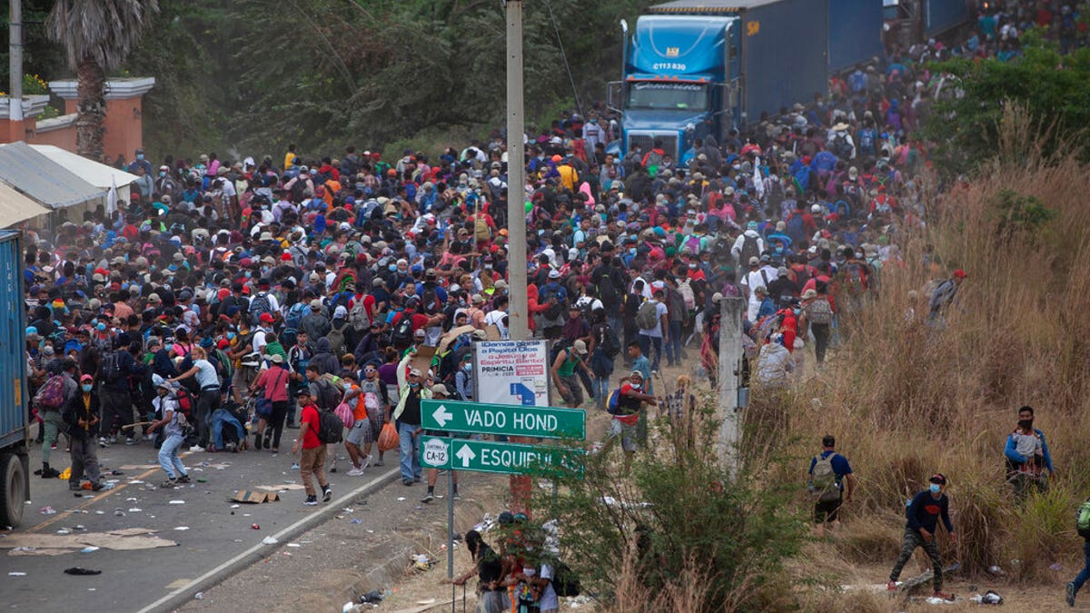 Honduran migrants, top, stand between cargo trucks as they confront Guatemalan soldiers and police blocking them from advancing toward the US, on the highway in Vado Hondo, Guatemala, Monday, Jan. 18, 2021.
