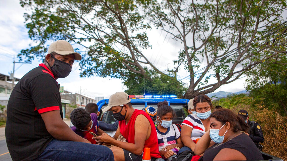 Honduran migrants sit in the bed of a police vehicle after they were detained in Chiquimula, Guatemala, Tuesday, Jan. 19, 2021. (AP Photo/Oliver de Ros)