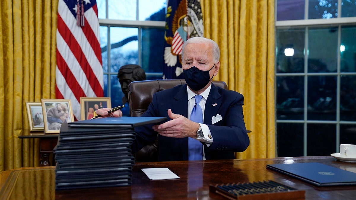 President Joe Biden signs his first executive orders in the Oval Office of the White House on Wednesday, Jan. 20, 2021, in Washington. (AP Photo/Evan Vucci)