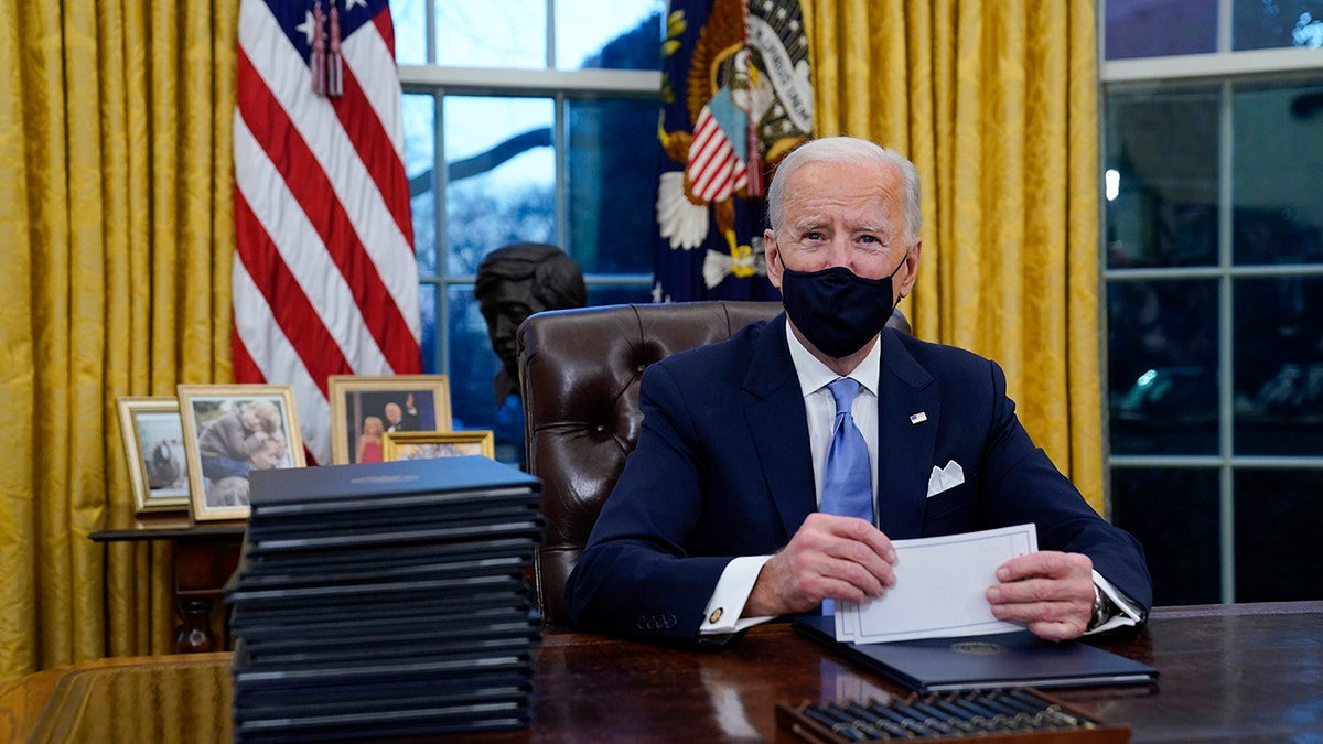 President Joe Biden pauses as he signs his first executive orders in the Oval Office 