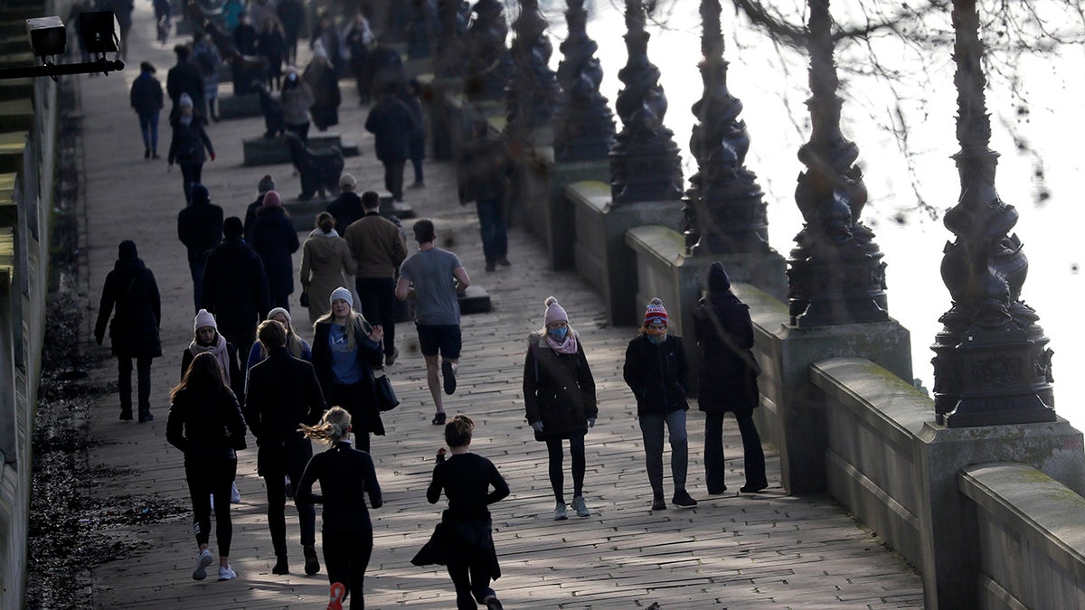 People exercise along the bank of the River Thames in London, Saturday, Jan. 23, 2021, during England's third national lockdown since the coronavirus outbreak began. The U.K. is under an indefinite national lockdown to curb the spread of the new variant, with nonessential shops, gyms and hairdressers closed, and people being told to stay at home. (AP Photo/Kirsty Wigglesworth)