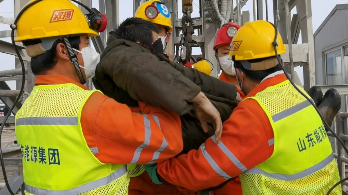 In this photo released by Xinhua News Agency, rescuers carry a miner who was trapped in a gold mine in Qixia City in east China's Shandong Province, Sunday, Jan. 24, 2021. Rescuers in China on Sunday lifted several trapped miners to the surface who were trapped for two weeks after an explosion in a northern gold mine, state media reported. (Luan Qincheng/Xinhua via AP)