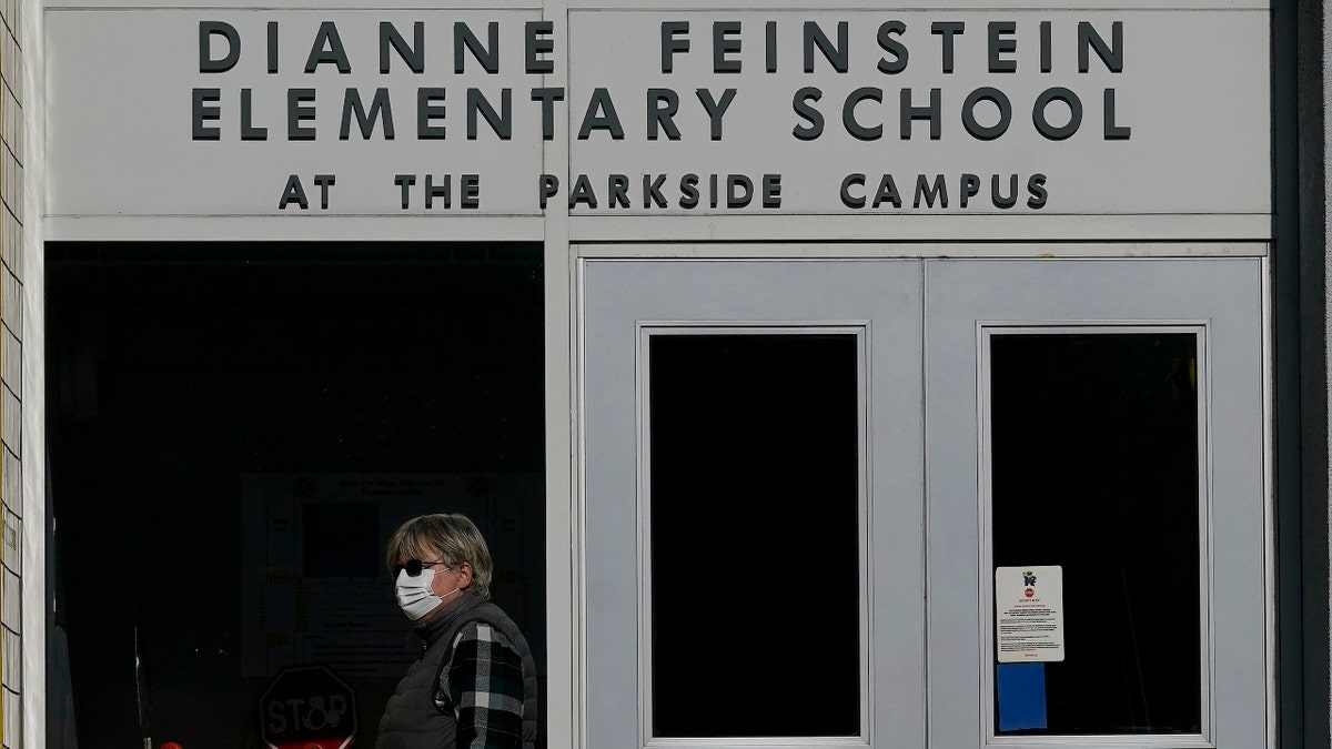 A pedestrian walks below a sign for Dianne Feinstein Elementary School in San Francisco on Dec. 17, 2020. (AP Photo/Jeff Chiu)