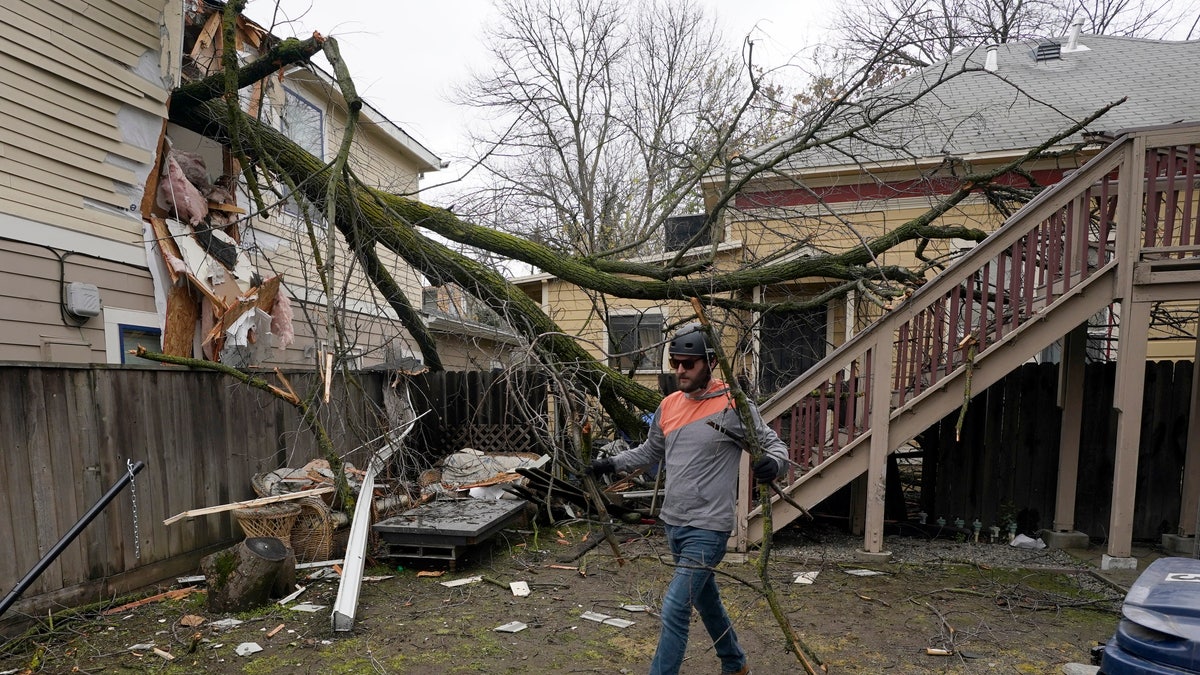 Eric Rose picks up debris from a tree that crashed through his neighbor's house and landed in his backyard during a storm in Sacramento, Calif., Wednesday, Jan. 27 2021. High-winds and rain pelted the region causing damage throughout the area. (AP Photo/Rich Pedroncelli)