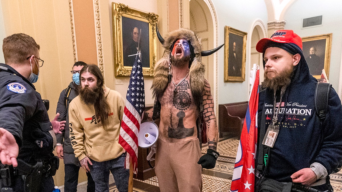 Jacob Chansley stands with Jan. 6 rioters at the U.S. Capitol