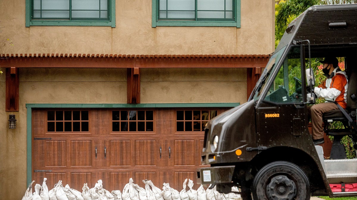 A delivery driver passes sandbags outside a Carmel, Calif. home on Thursday, Jan. 28, 2021. The area was evacuated Thursday morning as authorities feared heavy rains could send mud and water through the neighborhood. (AP Photo/Noah Berger)