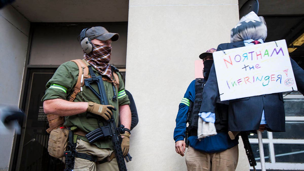 Armed second amendment supporters a carry mock-up of Gov. Ralph Northam on 9th Street near Capitol Square on Monday, Jan. 18, 2021, in Richmond, Va. Gov. Northam's administration supported an assault weapons ban bill that failed to pass during the 2020 Legislative term. (AP Photo/John C. Clark)