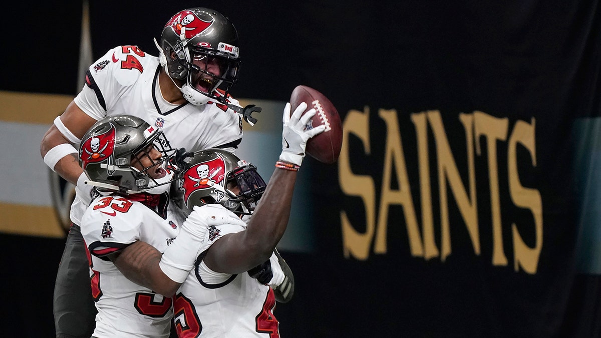 Tampa Bay Buccaneers inside linebacker Devin White, bottom right, celebrates after intercepting a pass with teammates Jordan Whitehead (33) and Carlton Davis (24) against the New Orleans Saints during the second half of an NFL divisional round playoff football game, Sunday, Jan. 17, 2021, in New Orleans. (AP Photo/Brynn Anderson)