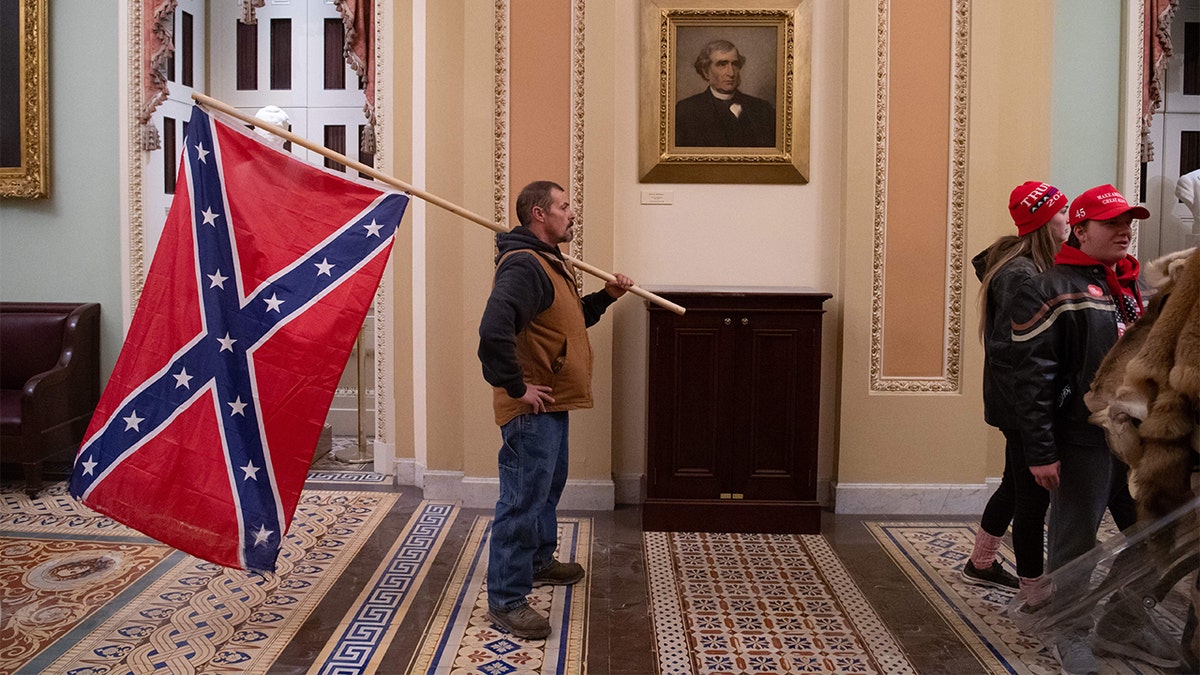 A supporter of President Trump holds a Confederate flag outside the Senate Chamber during a siege of the Capitol in Washington, D.C., on January 6, 2021. (Photo by SAUL LOEB / AFP) (Photo by SAUL LOEB/AFP via Getty Images)