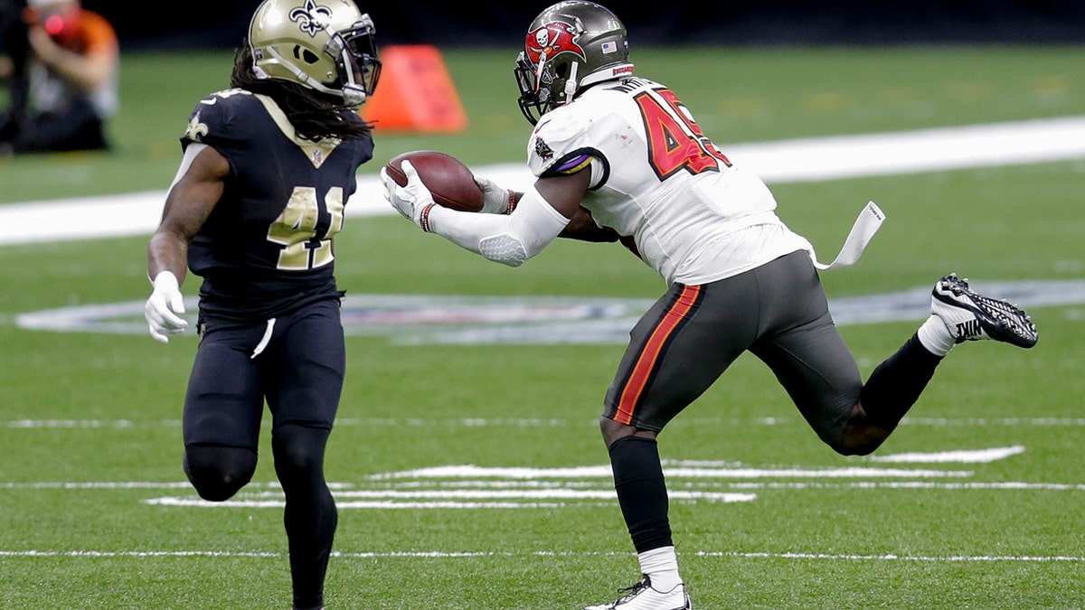 Tampa Bay Buccaneers inside linebacker Devin White, right, intercepts a pass in front of New Orleans Saints running back Alvin Kamara (41) during the second half of an NFL divisional round playoff football game, Sunday, Jan. 17, 2021, in New Orleans. (AP Photo/Brett Duke)