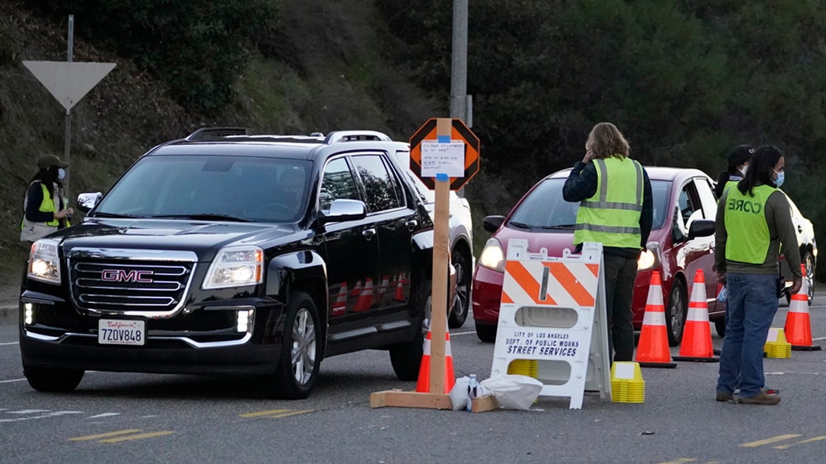 Drivers with a vaccine appointment enter a mega COVID-19 vaccination site set up in the parking lot of Dodger Stadium in Los Angeles Saturday, Jan. 30, 2021. One of the largest vaccination sites in the country was temporarily shut down Saturday because dozen of protesters blocked the entrance, stalling hundreds of motorists who had been waiting in line for hours, the Los Angeles Times reported. The Los Angeles Fire Department shut the entrance to the vaccination center at Dodger Stadium about 2 p.m. as a precaution, officials told the newspaper. The protesters had members of anti-vaccine and far-right groups, the Times reported. Some of them carried signs decrying the COVID-19 vaccine and shouting for people not to get the shots. (AP Photo/Damian Dovarganes)