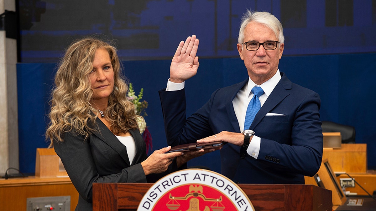 In this photo provided by the County of Los Angeles, incoming Los Angeles County District Attorney George Gascon is sworn in as his wife Fabiola Kramsky holds a copy of the Constitution during a mostly-virtual ceremony in downtown Los Angeles Monday, Dec. 7, 2020. Gascon, who co-authored a 2014 ballot measure to reduce some nonviolent felonies to misdemeanors, has promised more reforms to keep low-level offenders, drug users and those who are mentally ill out of jail and has said he won't seek the death penalty. (Bryan Chan/County of Los Angeles via AP)