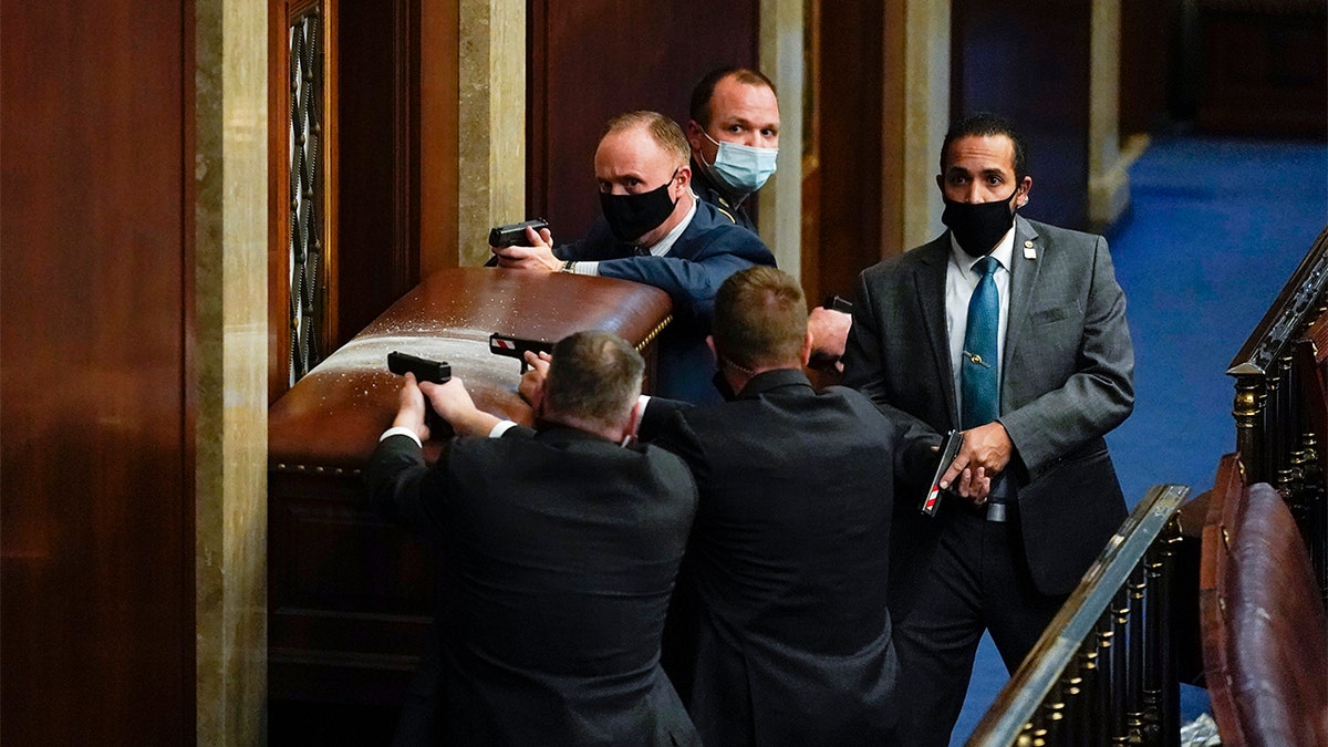 U.S. Capitol Police with guns drawn stand near a barricaded door as protesters try to break into the House Chamber at the U.S. Capitol on  Jan. 6, in Washington. (AP Photo/Andrew Harnik)