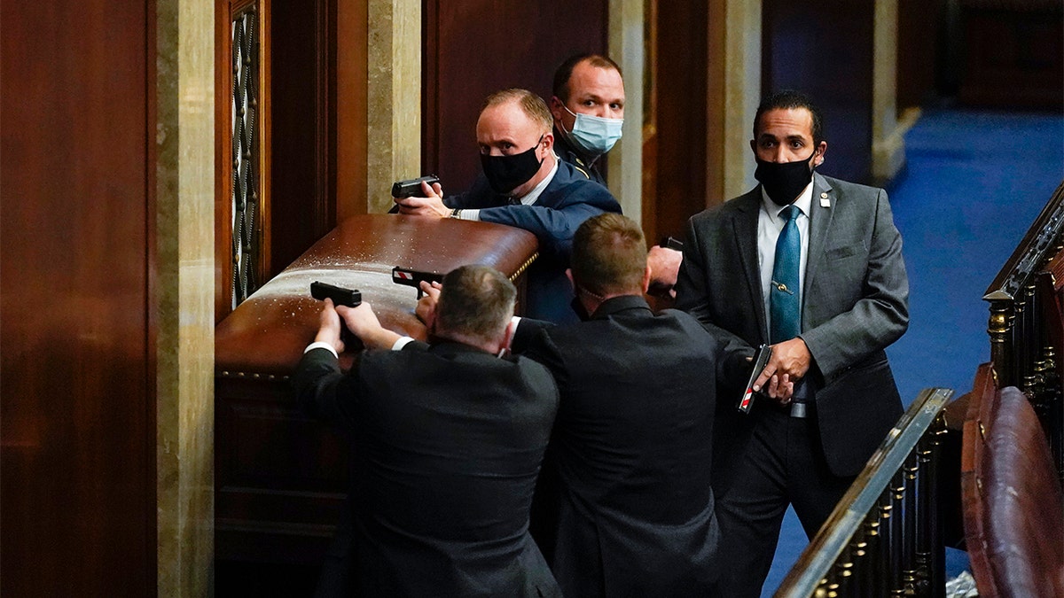 U.S. Capitol Police with guns drawn stand near a barricaded door as protesters try to break into the House Chamber at the U.S. Capitol on Jan. 6, in Washington. (AP Photo/Andrew Harnik)