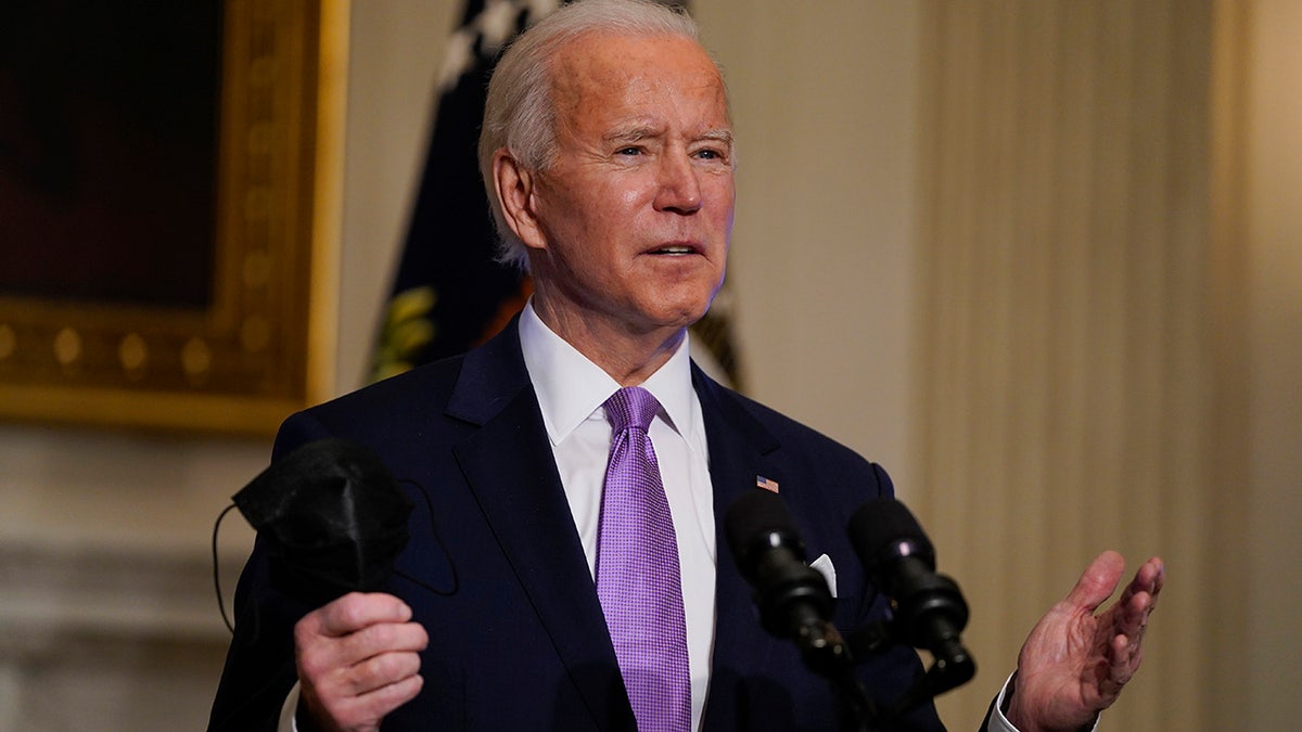 In this Jan. 26, 2021, photo, President Joe Biden holds his face mask as he speaks on COVID-19, in the State Dining Room of the White House in Washington. (AP Photo/Evan Vucci)