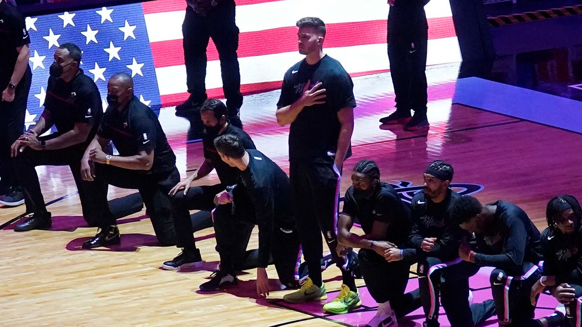 The Miami Heat team kneels during the playing of the national anthem before the first half of an NBA basketball game against the Miami Heat, Wednesday, Jan. 6, 2021, in Miami. (AP Photo/Marta Lavandier)