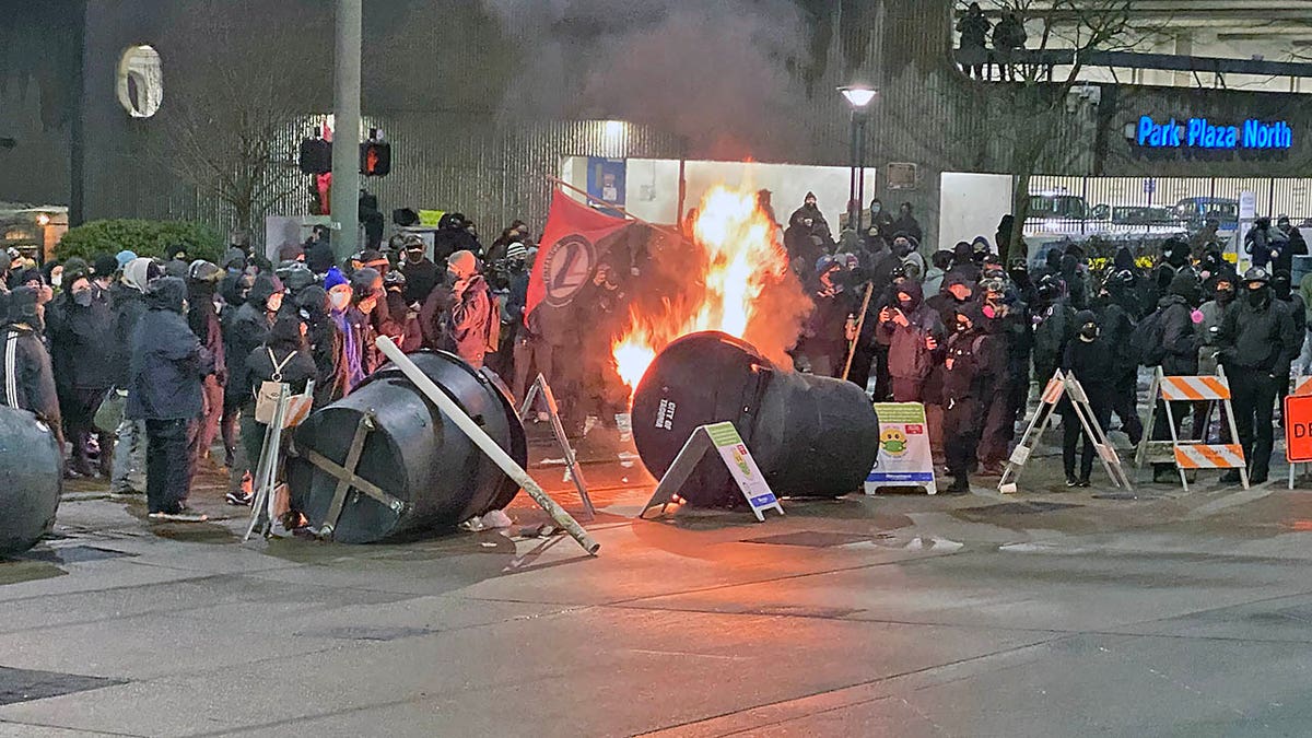 Antifa activists, dressed in black bloc, set small fires in an intersection by Frost Park in Tacoma, Wash. before their destructive march.