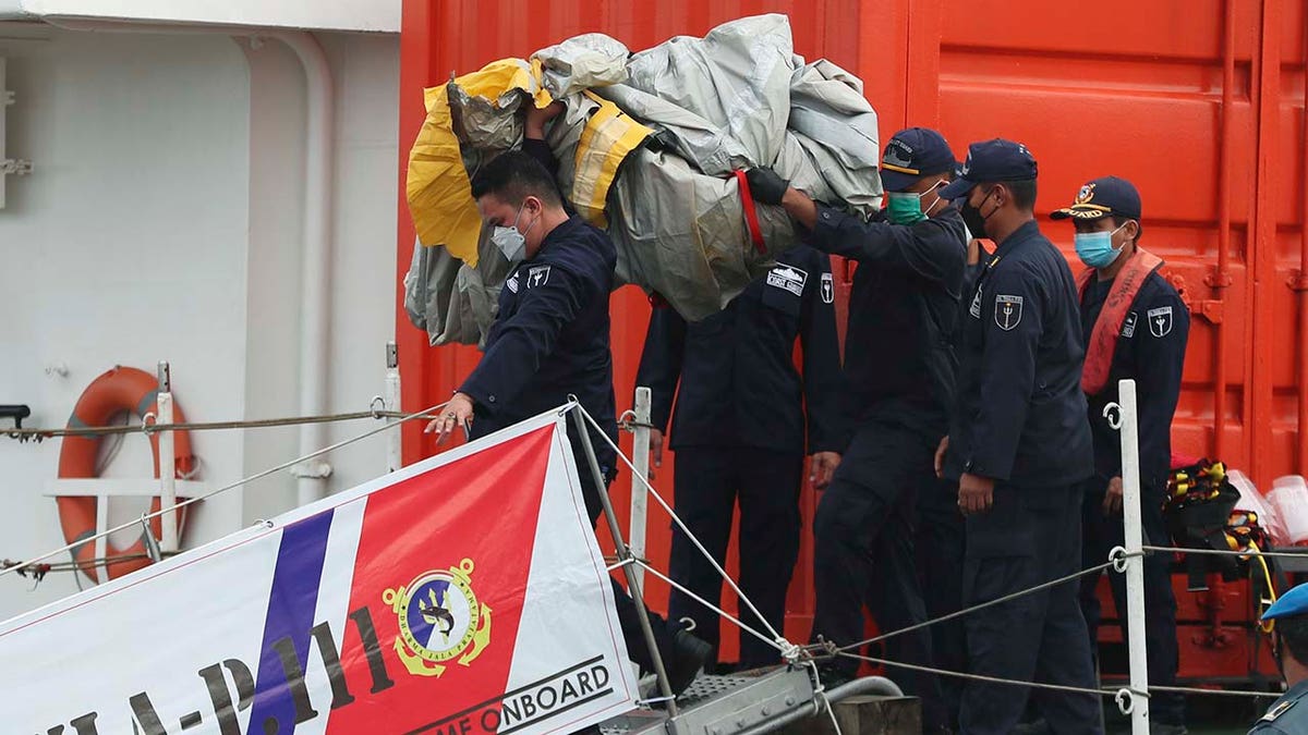 Rescuers carry debris found in the waters around the location where a Sriwijaya Air passenger jet has lost contact with air traffic controllers shortly after the takeoff, at the search and rescue command center at Tanjung Priok Port in Jakarta, Indonesia, Sunday, Jan. 10, 2021. (Associated Press)