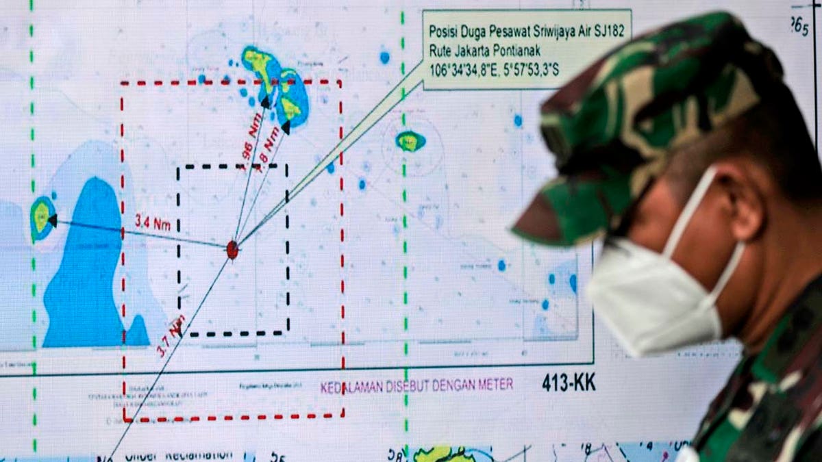 An Indonesian soldier walks past a map showing the location where a Sriwijaya Air passenger jet has lost contact with air traffic controllers shortly after taking off, at the search and rescue command center at Tanjung Priok Port in Jakarta, Indonesia, Sunday, Jan. 10, 2021. (Associated Press)