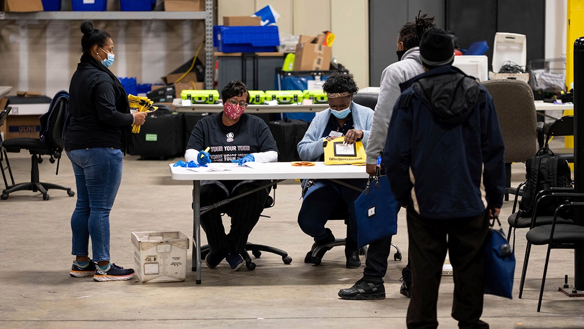 Elections workers at the Fulton County Georgia elections warehouse check in voting machine memory cards that store ballots following the Senate runoff election in Atlanta on Tuesday, Jan. 5, 2021.  (AP Photo/Ben Gray)