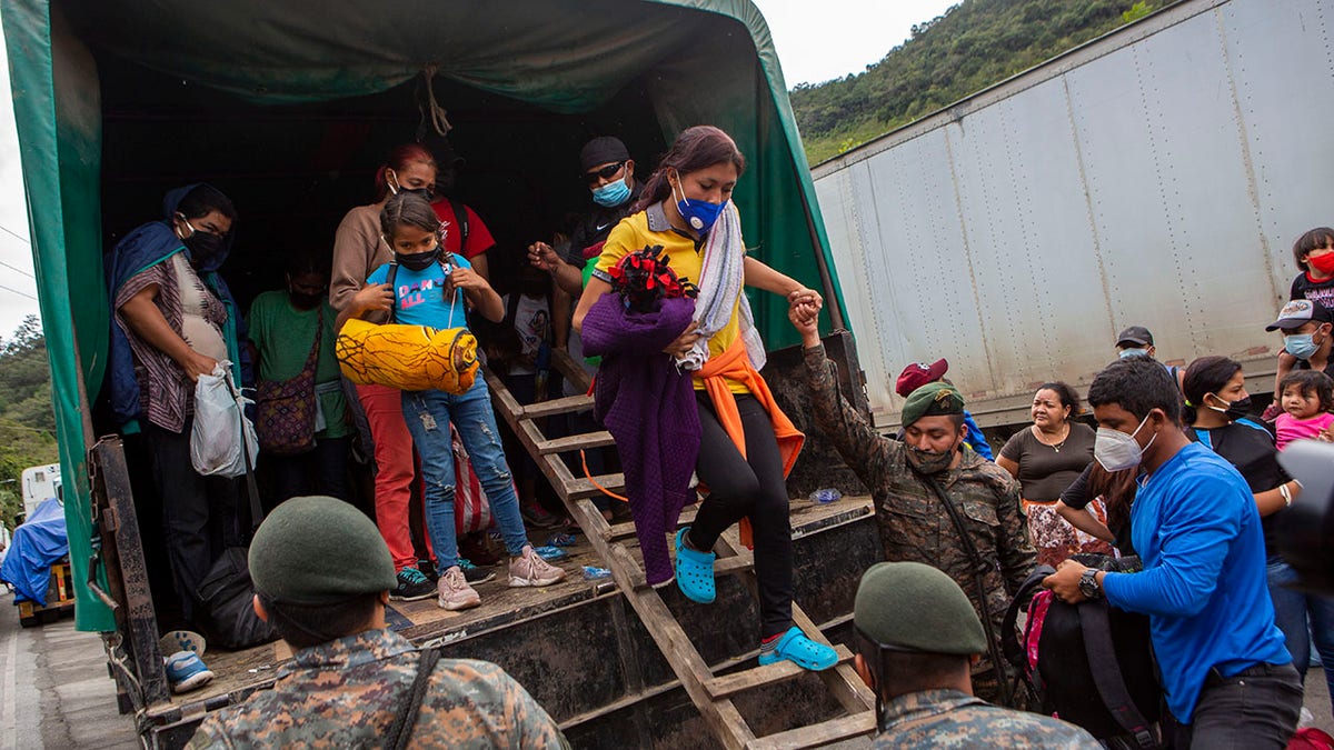 A Honduran migrant woman is helped off a Guatemalan army truck after being returned to El Florido, Guatemala, one of the border points between Guatemala and Honduras, Tuesday, Jan. 19, 2021. (AP Photo/Oliver de Ros)