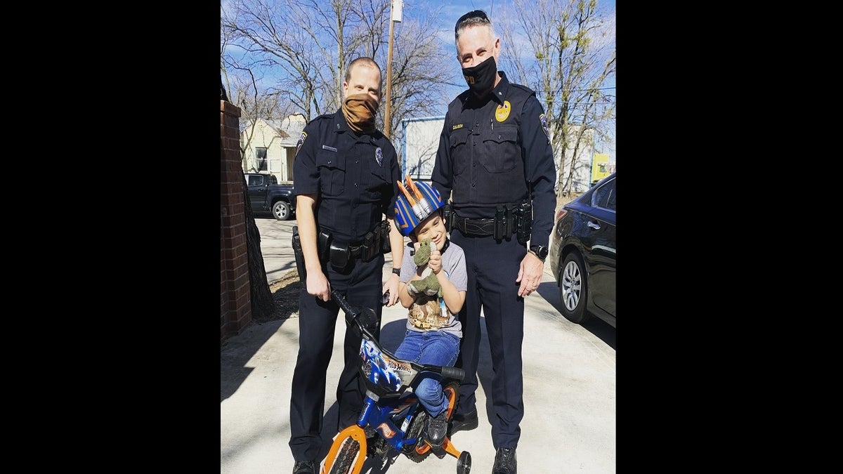 Detective Josh Smith, left, helped present a new bicycle to the child after his was destroyed. (Irving Police Department)