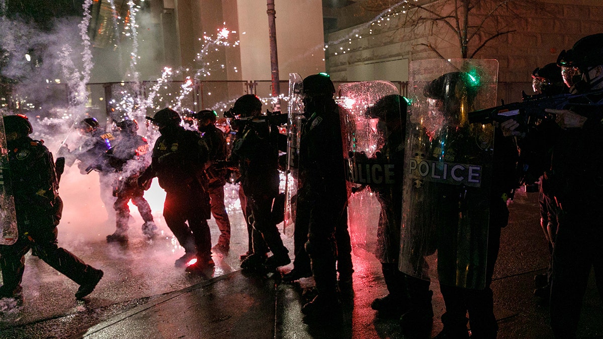 PORTLAND, OR, USA - DECEMBER 31: Protesters throw fireworks at police officers during a protest against police brutality near the federal courthouse in Portland, Oregon, USA, on December 31, 2020. shooting)