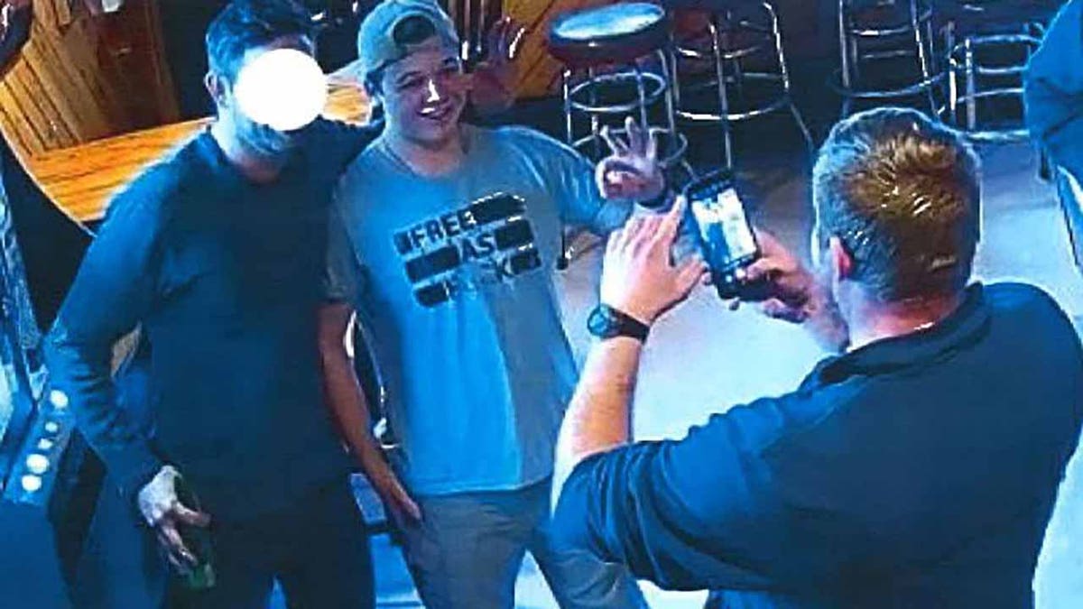 As part of a sworn affidavit in Kenosha County Circuit Court, Assistant District Attorney Thomas C. Binger submitted several still images from the video which show Kyle Rittenhouse posing for several photographs in a t-shirt that reads "Free as F**k." In each photograph, the defendant and the other adult males are flashing the "OK" sign.
