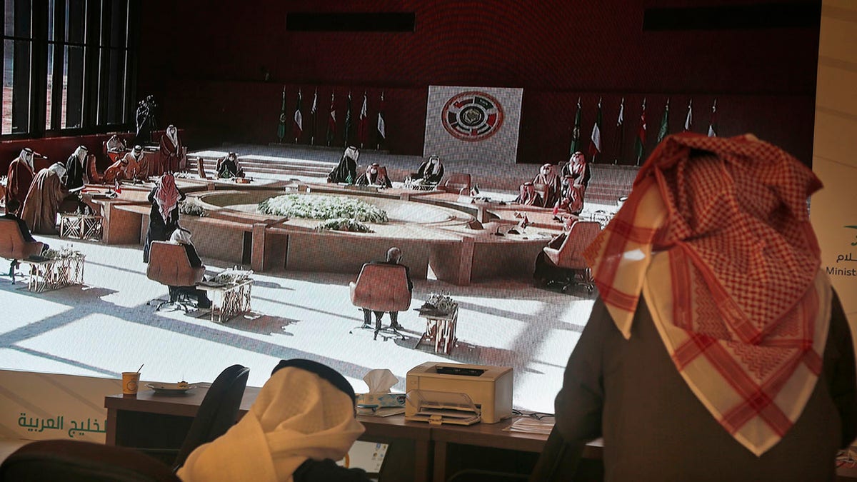 Saudi journalists watch a screen showing the meeting of the 41st Gulf Cooperation Council (GCC) taking place in Al Ula, Saudi Arabia, Tuesday, Jan. 5, 2021. Qatar's ruling emir arrived in Saudi Arabia to attend a high-level summit of Arab leaders following an announcement that the kingdom would end its yearslong embargo on the tiny Gulf state. (AP Photo/Amr Nabil)