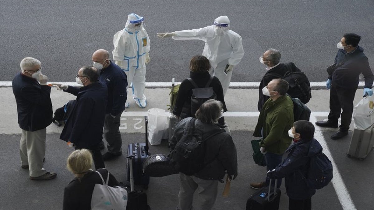 A worker in protective coverings directs members of the World Health Organization (WHO) team on their arrival at the airport in Wuhan in central China's Hubei province on Thursday, Jan. 14, 2021. (AP Photo/Ng Han Guan) (AP Photo/Ng Han Guan)