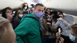Alexei Navalny is surrounded by journalists inside the plane prior to his flight to Moscow in the Airport Berlin Brandenburg (BER) in Schoenefeld, near Berlin, Germany, Sunday, Jan. 17, 2021.