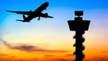 airplane flying by tower at sunset