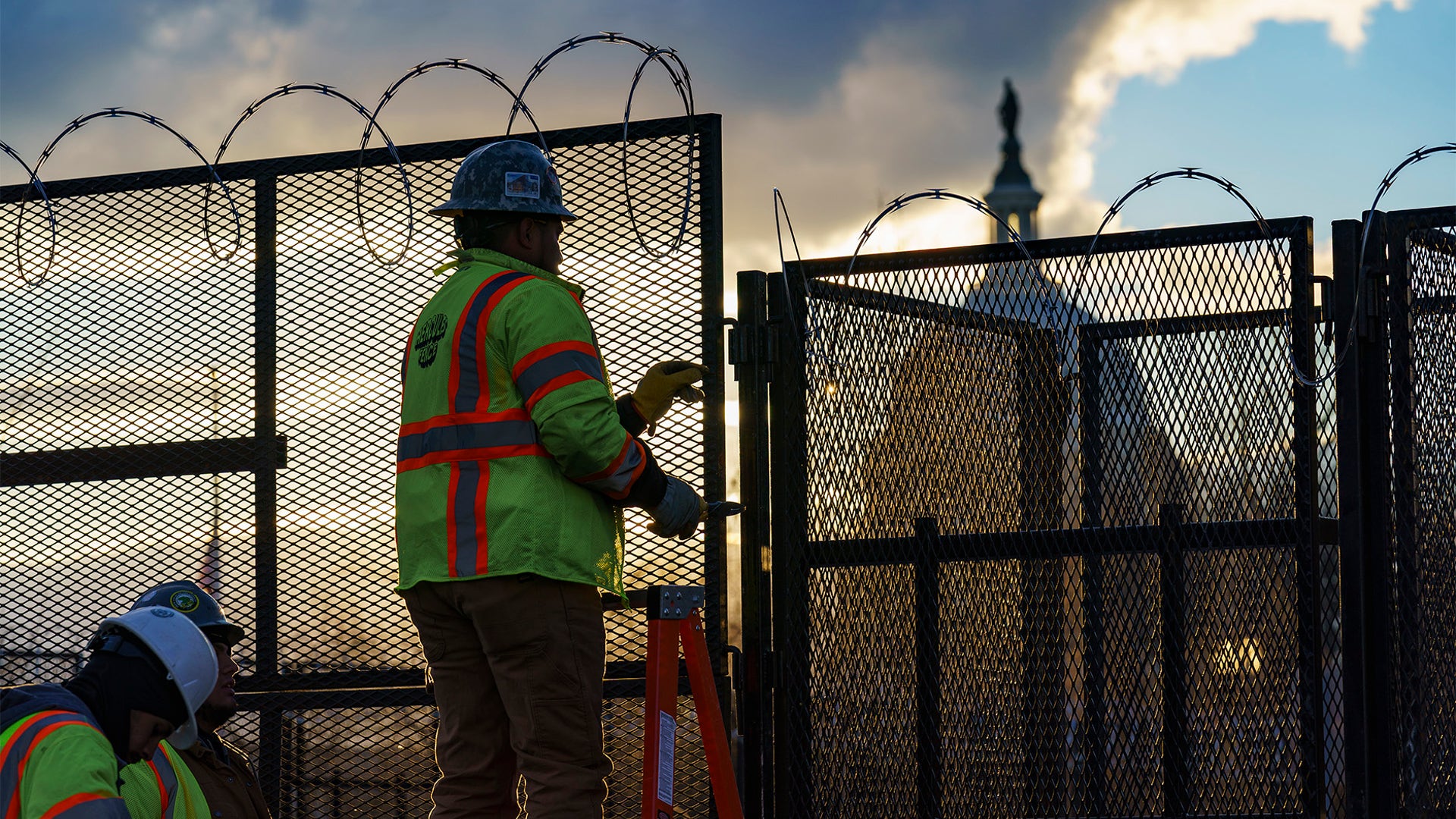 Workers install razor wire atop fencing around the U.S. Capitol perimeter at sunset, in Washington, Monday, Jan. 18, 2021.  (AP Photo/J. Scott Applewhite)