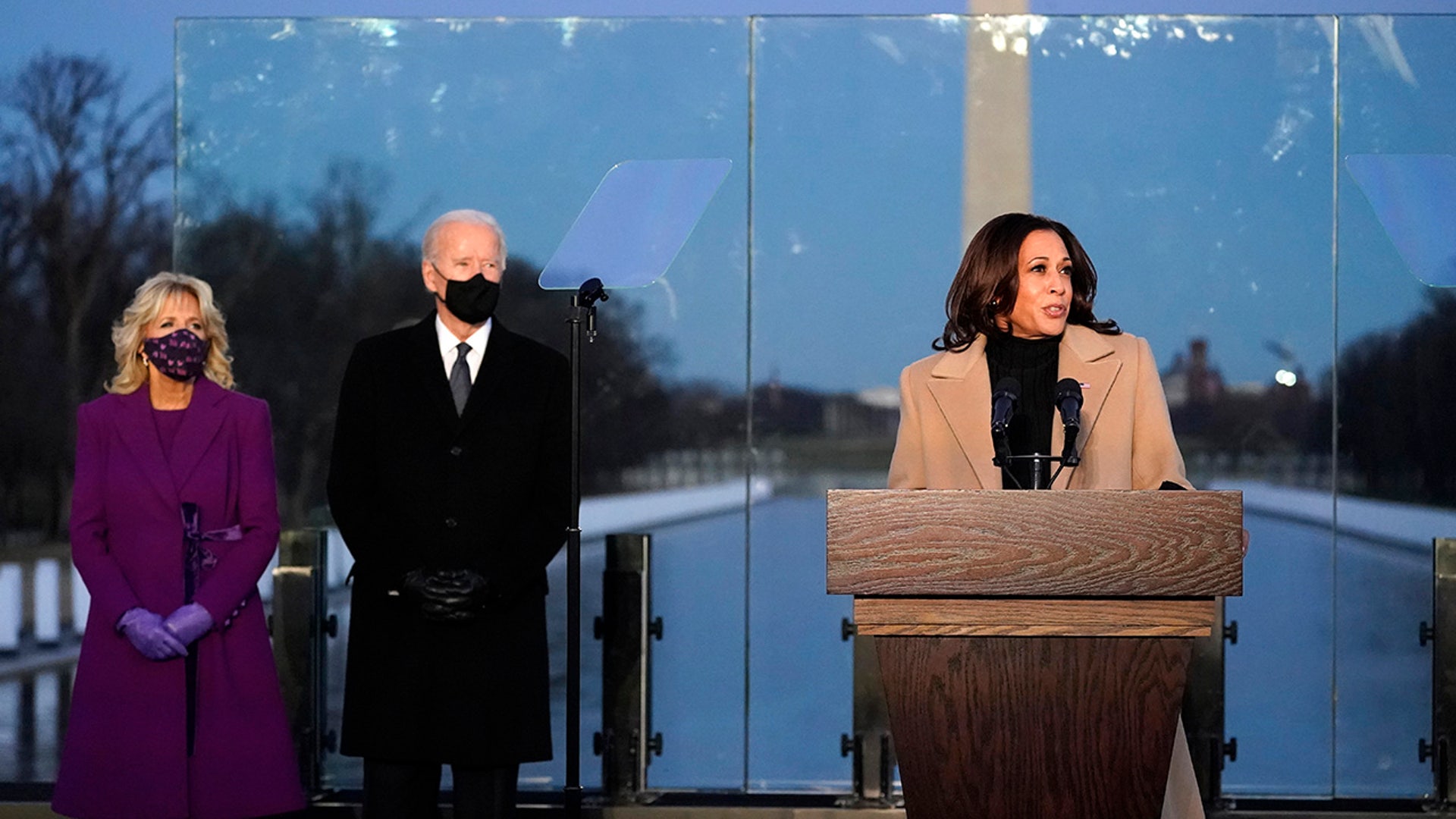 President-elect Joe Biden and his wife, Jill Biden, listen as Vice President-elect Kamala Harris speaks during a COVID-19 memorial, with lights placed around the Lincoln Memorial Reflecting Pool, Tuesday, Jan. 19, 2021, in Washington.