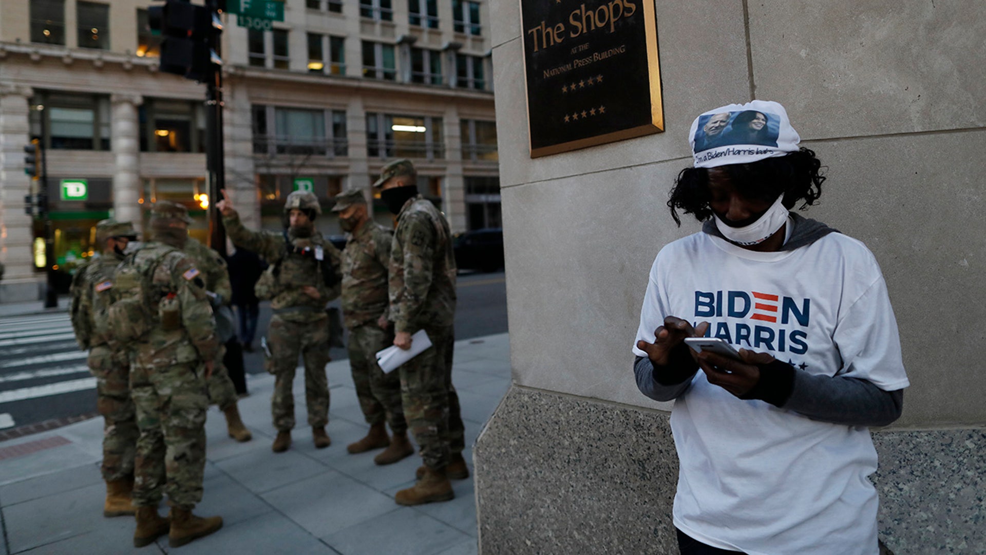 A Biden-Harris supporter stands at a corner as National Guards deploy around the city ahead of President-elect Joe Biden's inauguration ceremony, Tuesday, Jan. 19, 2021, in Washington.
