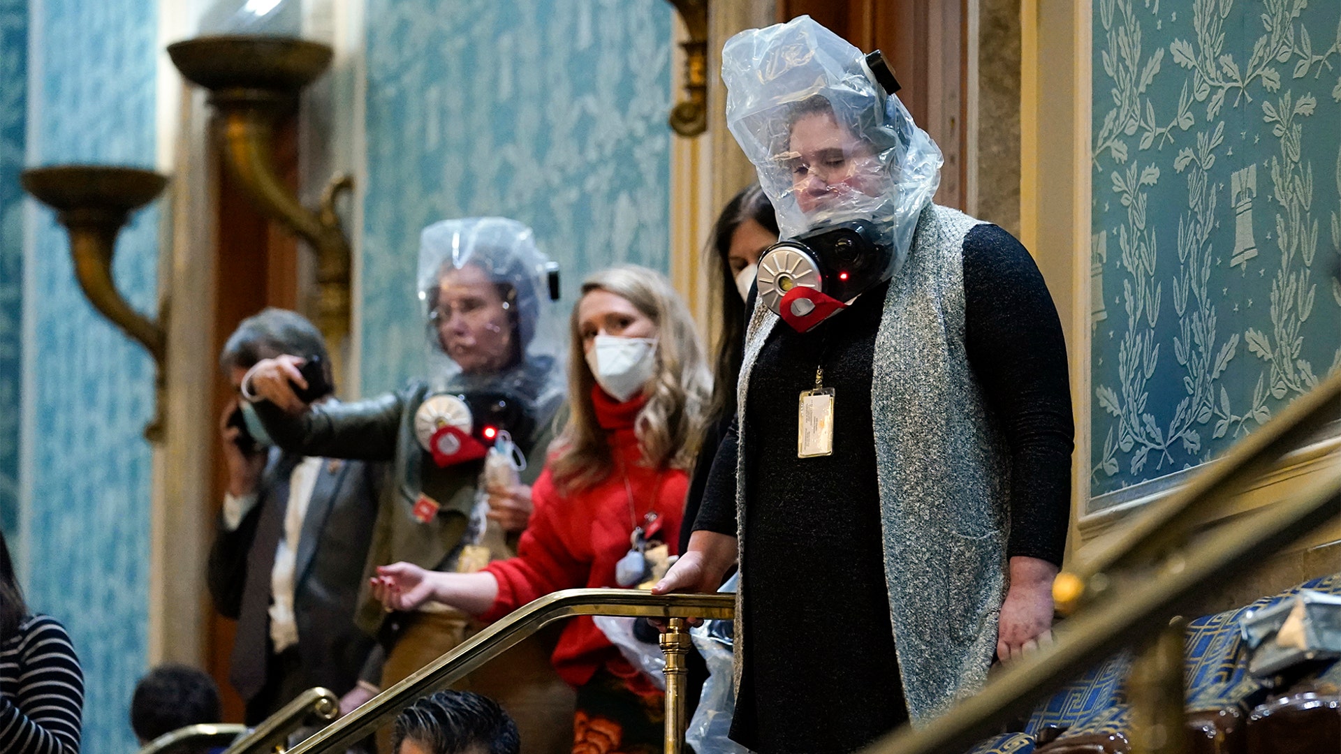 People shelter in the House gallery as protesters try to break into the House Chamber at the U.S. Capitol on Wednesday, Jan. 6, 2021, in Washington.