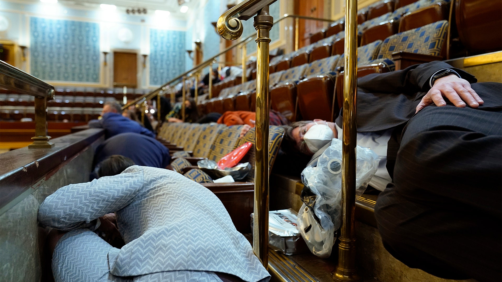 People shelter in the House gallery as protesters try to break into the House Chamber at the U.S. Capitol on Wednesday, Jan. 6, 2021, in Washington.