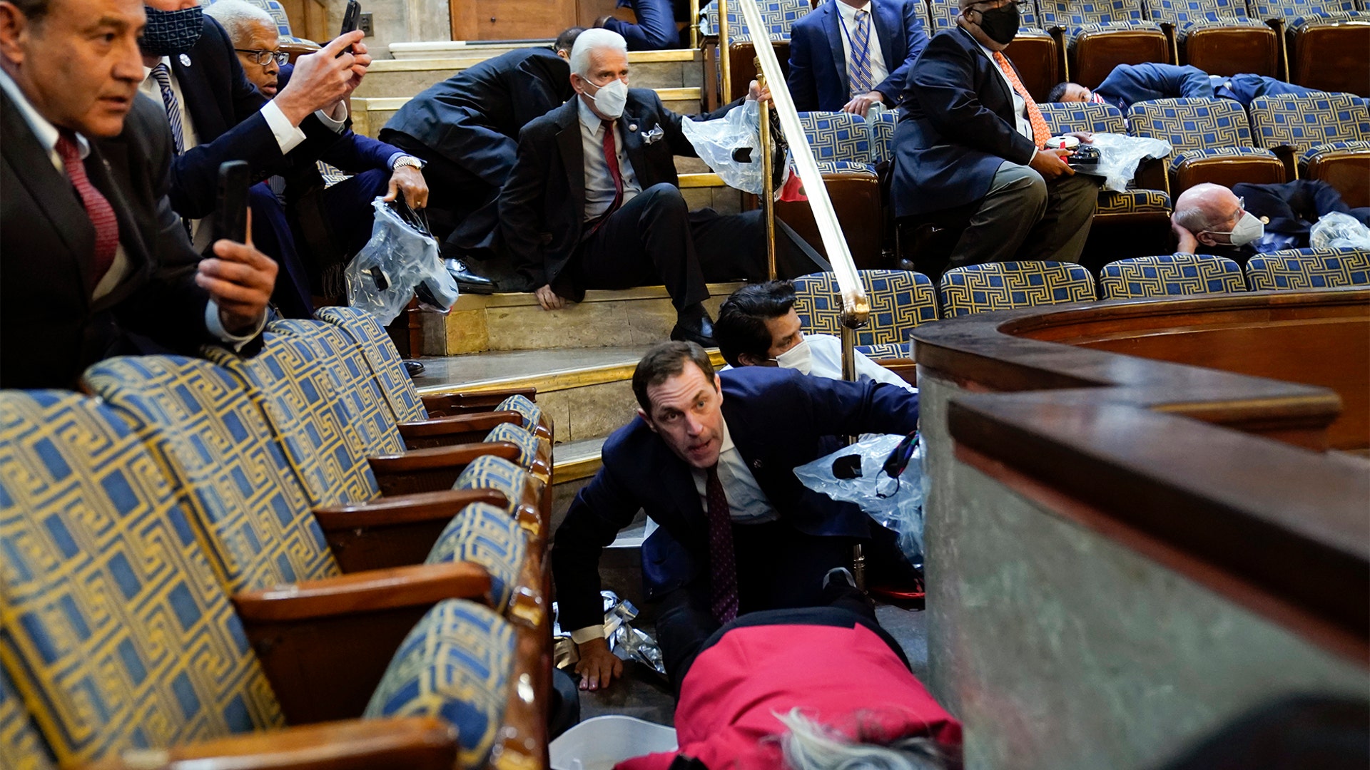 People shelter in the House gallery as protesters try to break into the House Chamber at the U.S. Capitol on Wednesday, Jan. 6, 2021, in Washington.