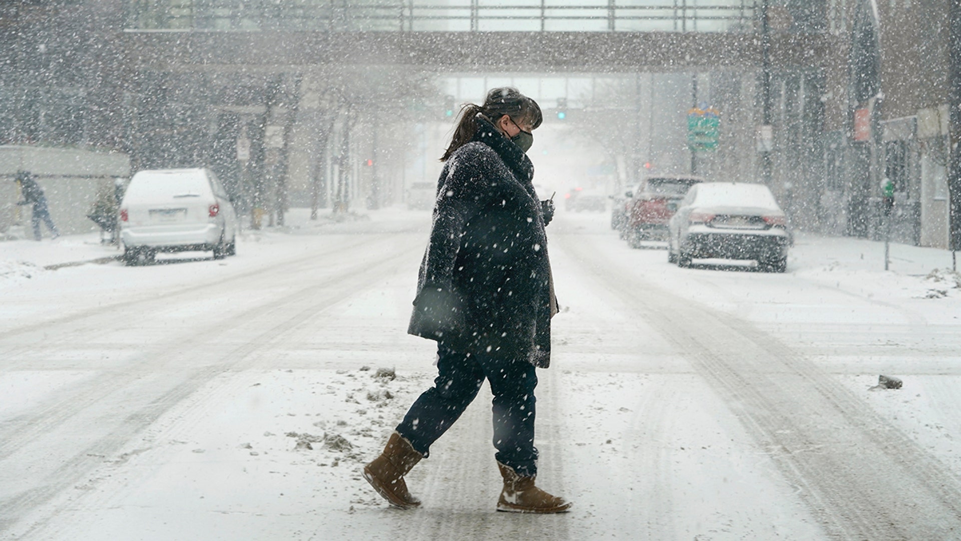 A pedestrian crosses a snow-covered street, Monday, Jan. 25, 2021, in downtown Des Moines, Iowa. A major winter storm is expected to blanket a large swath of the middle of the country with snow Monday and disrupt travel as more than a foot of snow falls in some areas.