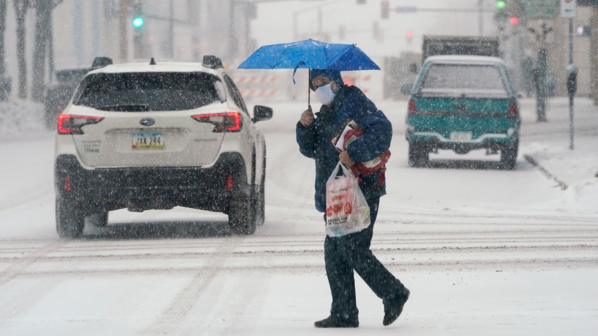 A pedestrian crosses a snow-covered street, Monday, Jan. 25, 2021, in downtown Des Moines, Iowa. A major winter storm is expected to blanket a large swath of the middle of the country with snow Monday and disrupt travel as more than a foot of snow falls in some areas.