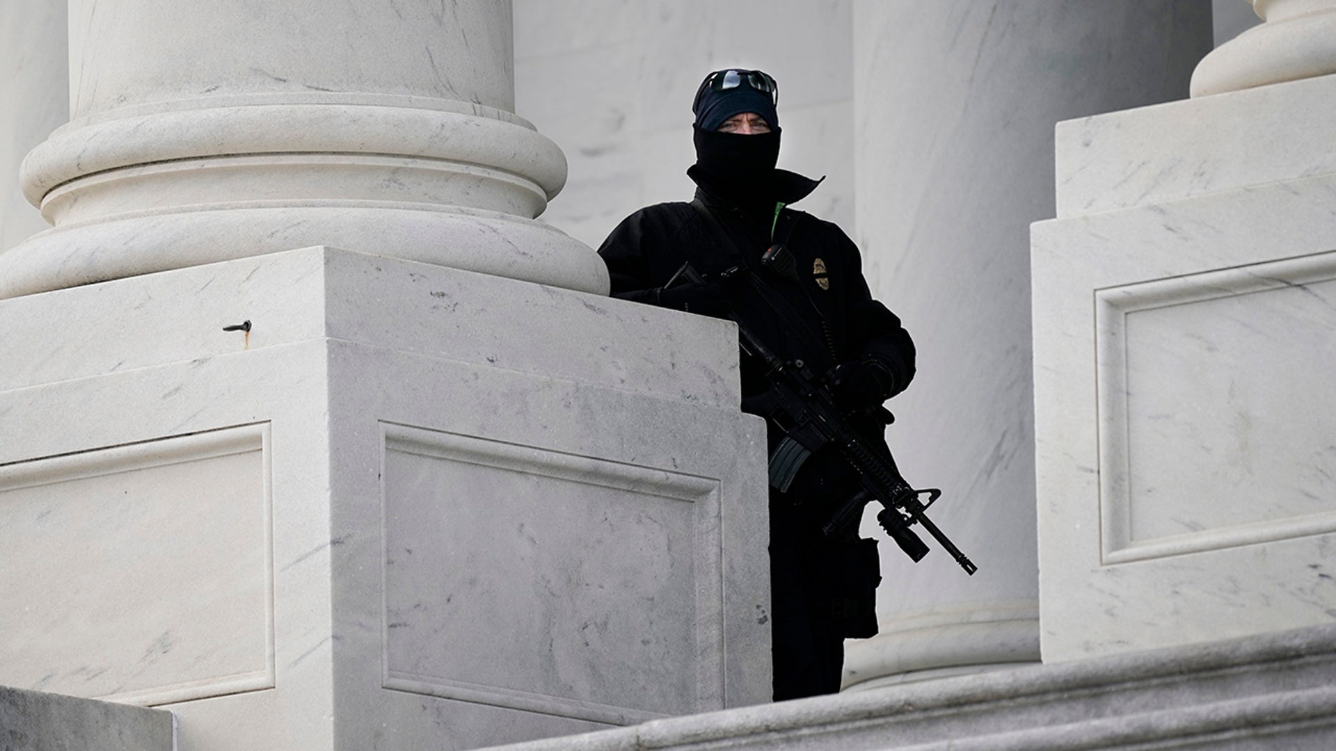 An armed U.S. Capitol Police officer looks out from the East side of the Capitol, during a rehearsal for President-elect Joe Biden's inauguration ceremony, at the Capitol in Washington, Monday, Jan. 18, 2021.