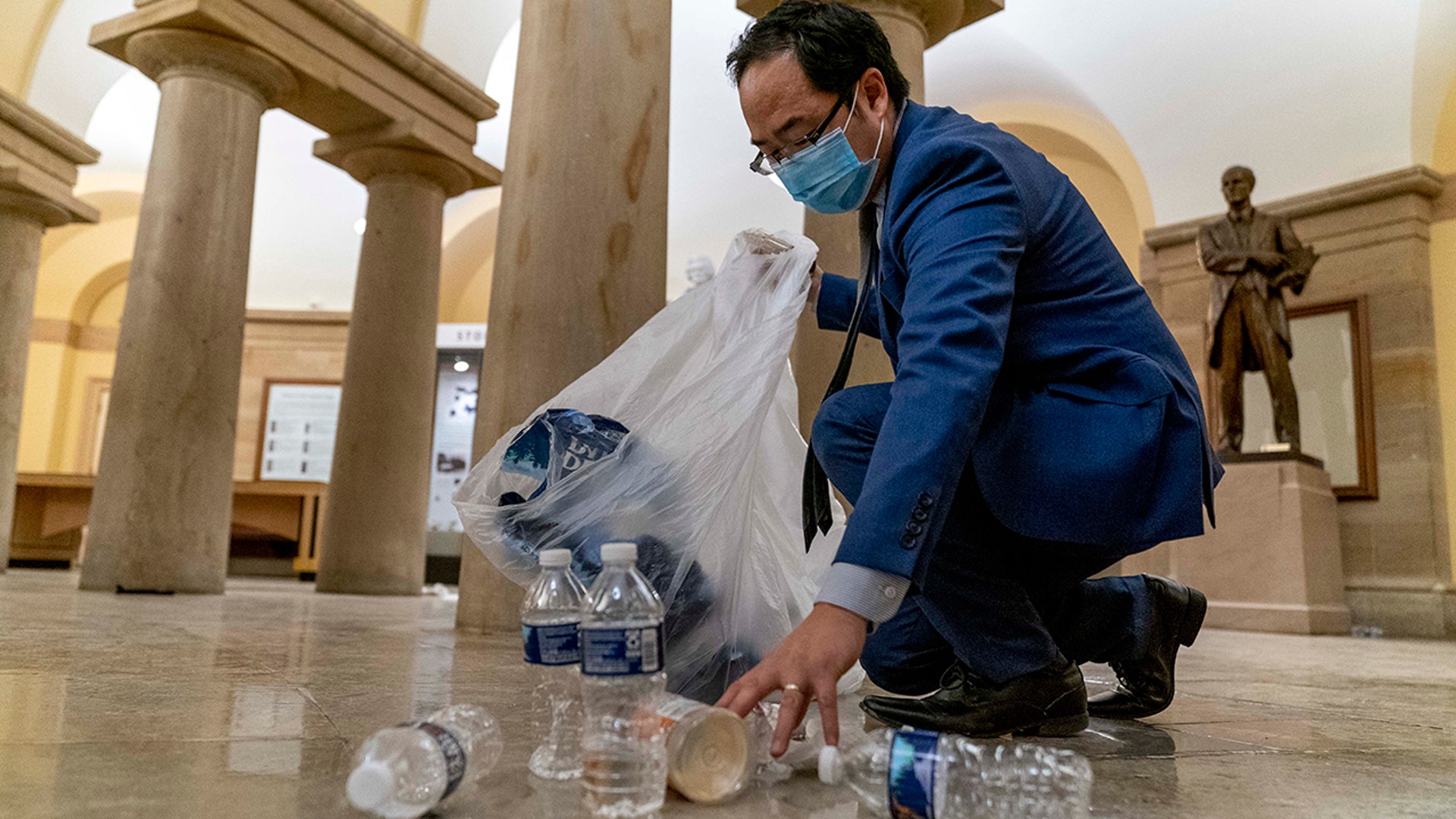 Rep. Andy Kim, D-N.J., cleans up debris and trash strewn across the floor in the early morning hours of Thursday, Jan. 7, 2021, after protesters stormed the Capitol in Washington, on Wednesday.