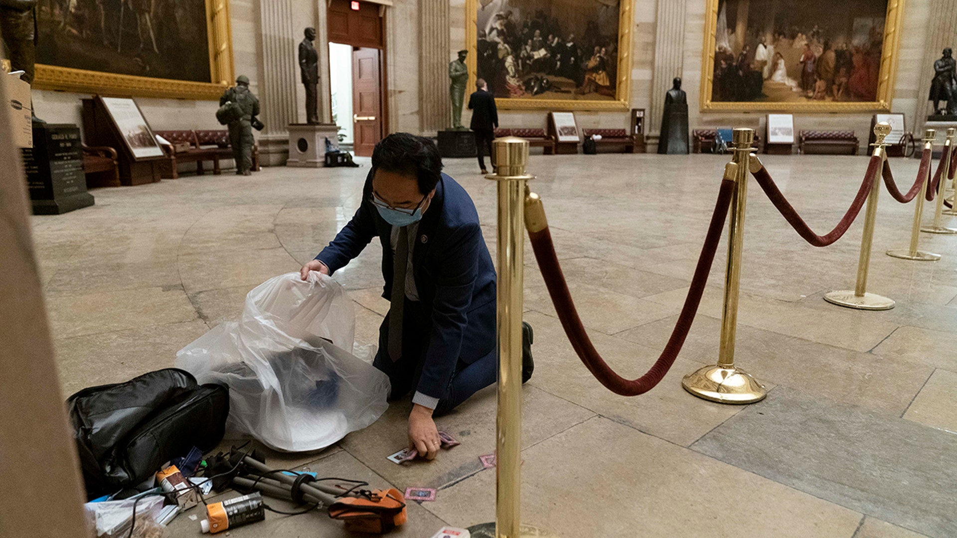 Rep. Andy Kim, D-N.J., cleans up debris and personal belongings strewn across the floor of the Rotunda in the early morning hours of Thursday, Jan. 7, 2021, after protesters stormed the Capitol in Washington, on Wednesday