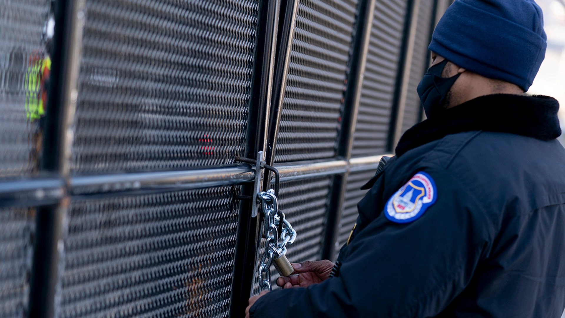 A U.S. Capitol Police checks a lock on a fence installed along the perimeter of the Capitol building on Capitol Hill in Washington, Thursday, Jan. 14, 2021.