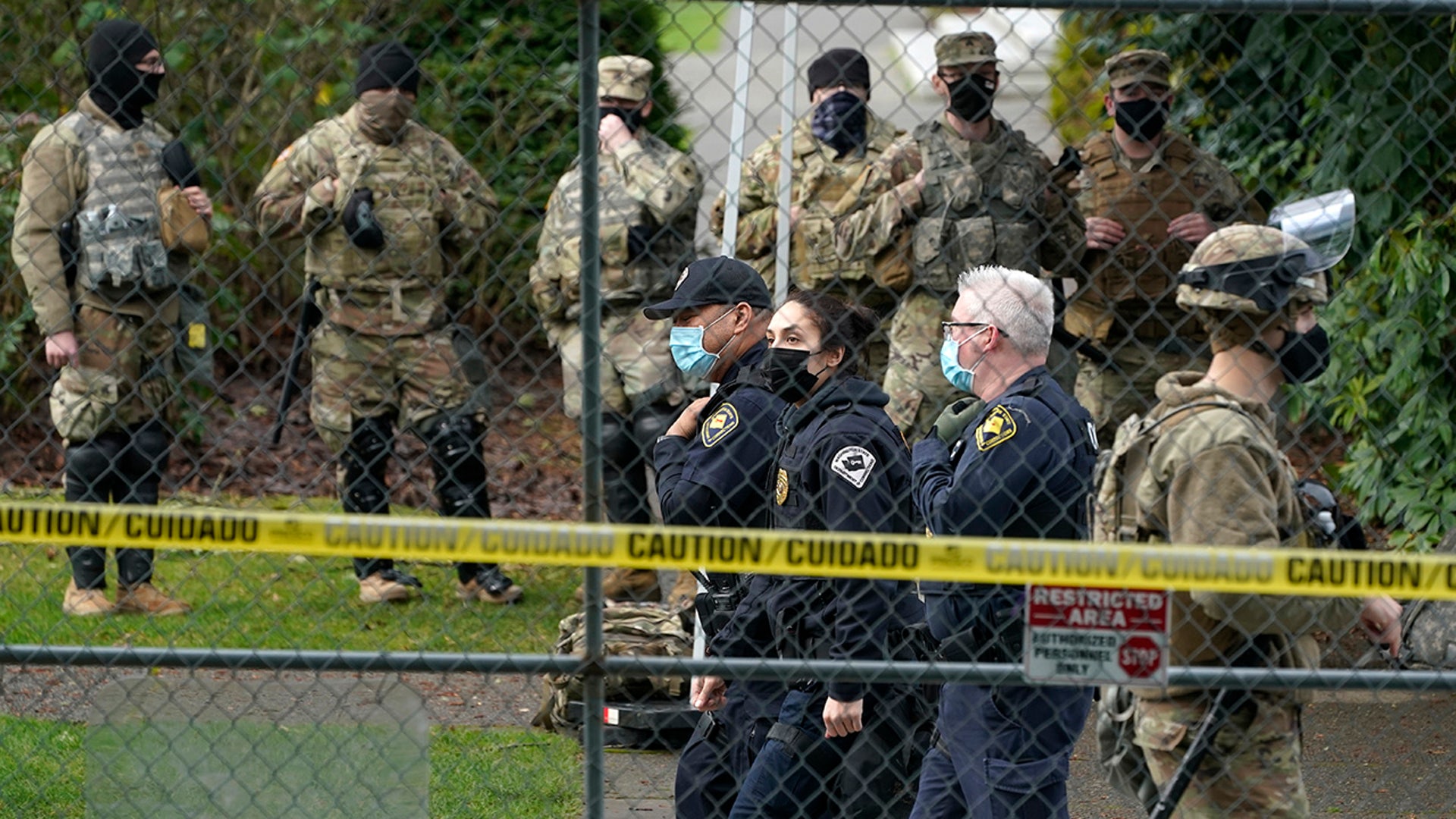 Washington State Patrol troopers walk near National Guard members standing watch along a perimeter fence, Sunday, Jan. 17, 2021, at the Capitol in Olympia, Wash. Security is expected to remain tight at the Capitol at least through the inauguration of President-elect Joe Biden on Wednesday. (AP Photo/Ted S. Warren)