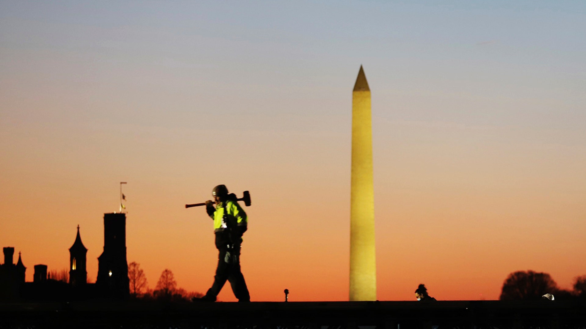A construction worker carries a hammer on his shoulder on Wednesday, Jan. 13, 2021 at the National Mall in Washington, as a stage is prepared for the 2021 Democrat Joe Biden's presidential inauguration. (AP Photo/Shafkat Anowar)