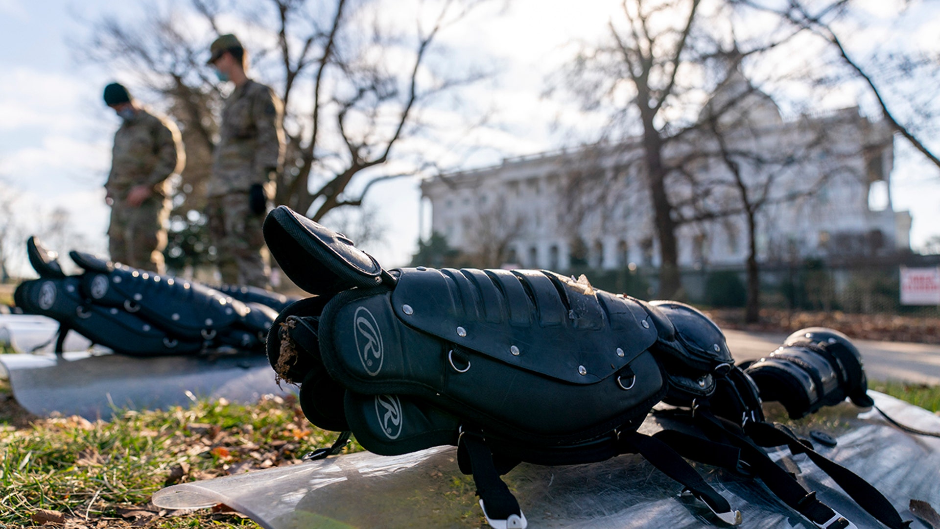 The Dome of the Capitol building is visible as members of the National Guard stand in front of riot gear laid out on a field on Capitol Hill in Washington, Wednesday, Jan. 13, 2021. (AP Photo/Andrew Harnik)