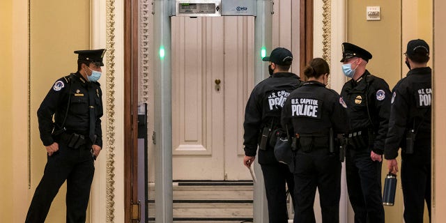U.S. Capitol Police survey the corridor around the House of Representatives chamber after enhanced security protocols were enacted, including metal detectors for lawmakers, after a mob loyal to President Donald Trump stormed the Capitol, in Washington, Tuesday, Jan. 12, 2021. (AP Photo/J. Scott Applewhite)